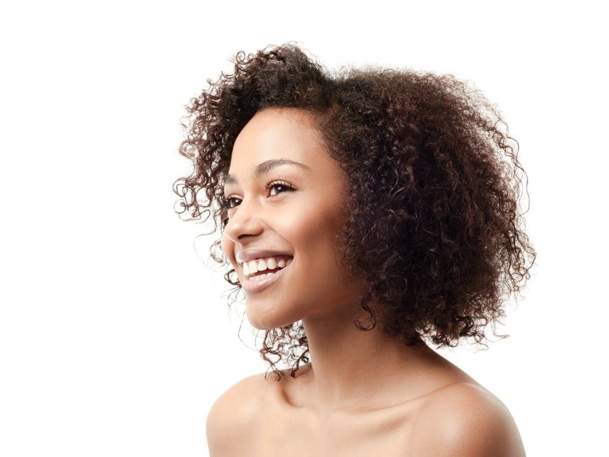 Mujer de perfil con una sonrisa y encías sanas (imagen ilustrativa)